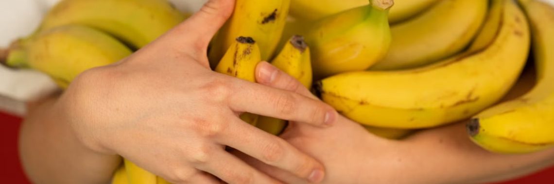 Crop unrecognizable person with bundles of tasty ripe bananas with pleasant aroma and spots on peel