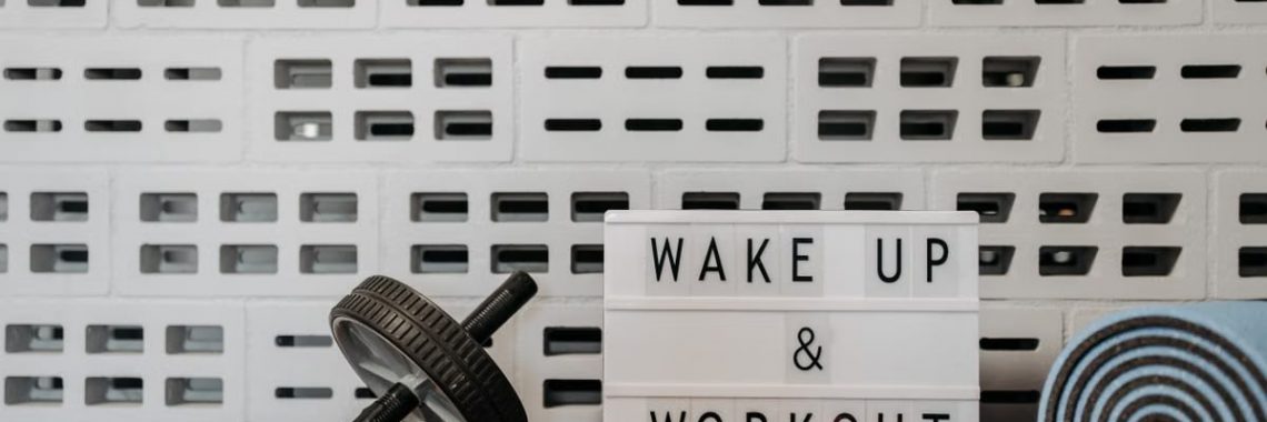 Fitness gear and motivational sign in home gym setup against a brick wall.